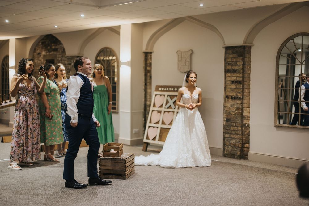 A wedding celebration moment with guests gathered in an elegant arched hallway with stone columns at Cave Castle - by Grimsby photographers.