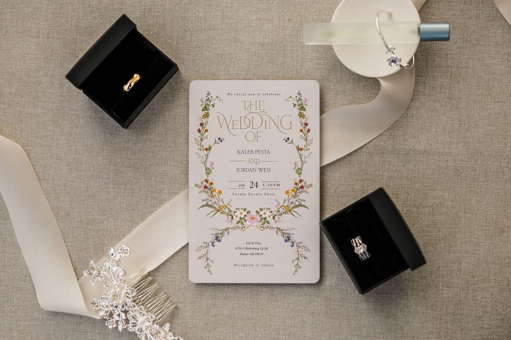 Wedding invitations and accessories arranged on neutral linen background.