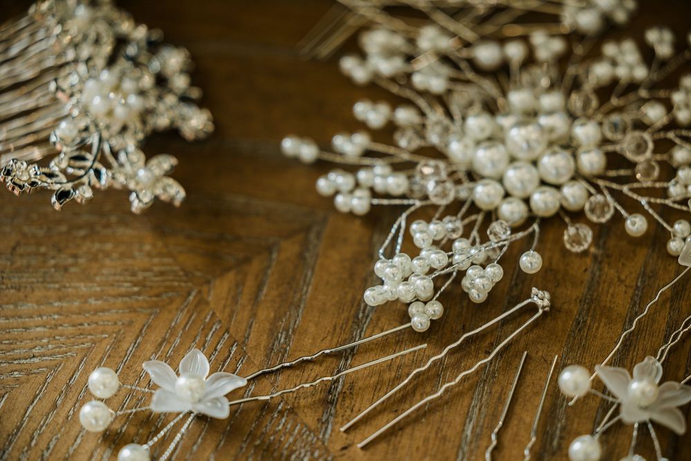 Delicate white floral hair accessories and pins arranged on wooden surface.