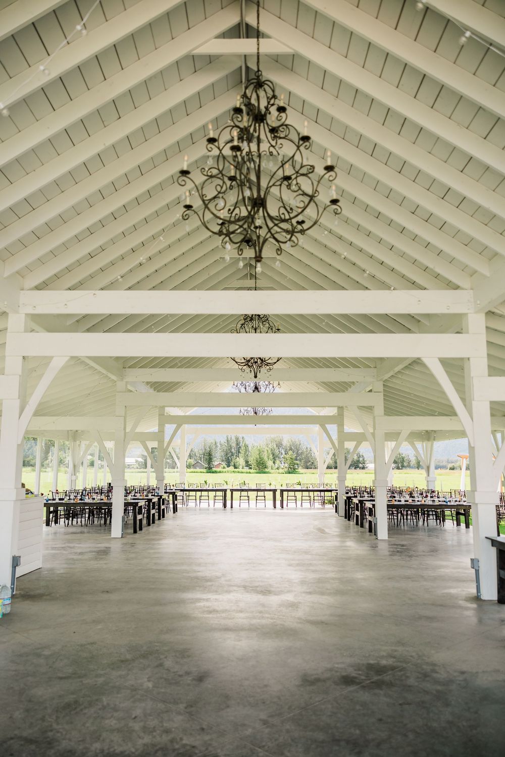 Large white pavilion venue interior with vaulted ceiling and chandeliers.