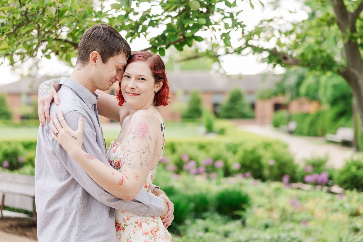 A couple embraces outdoors in a garden setting with flowering plants and greenery in the background at Cantigny Park