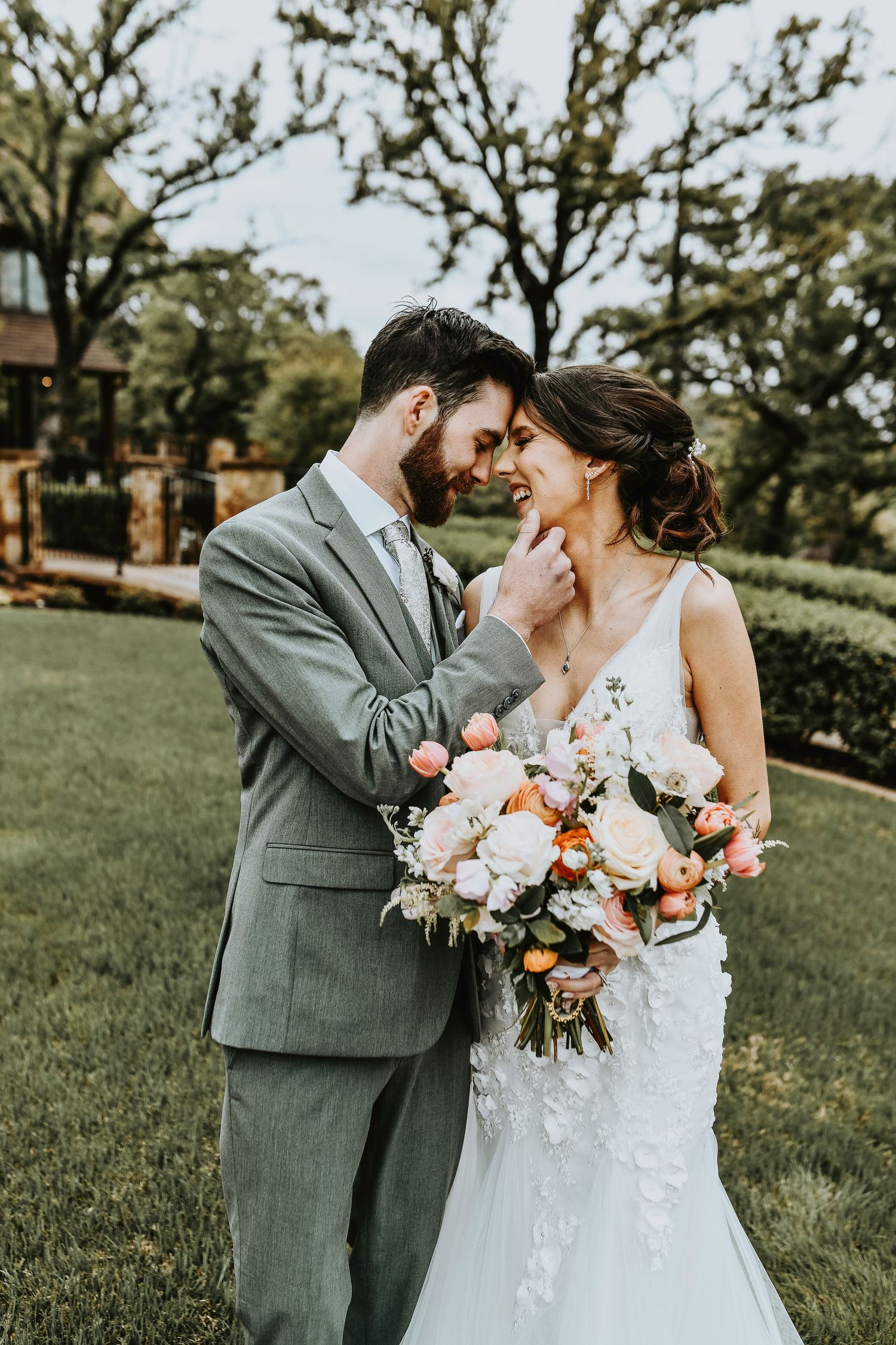 Bride and groom having a candid moment under the iconic bridge at The Lodge, with spring flowers and greenery framing the photo.