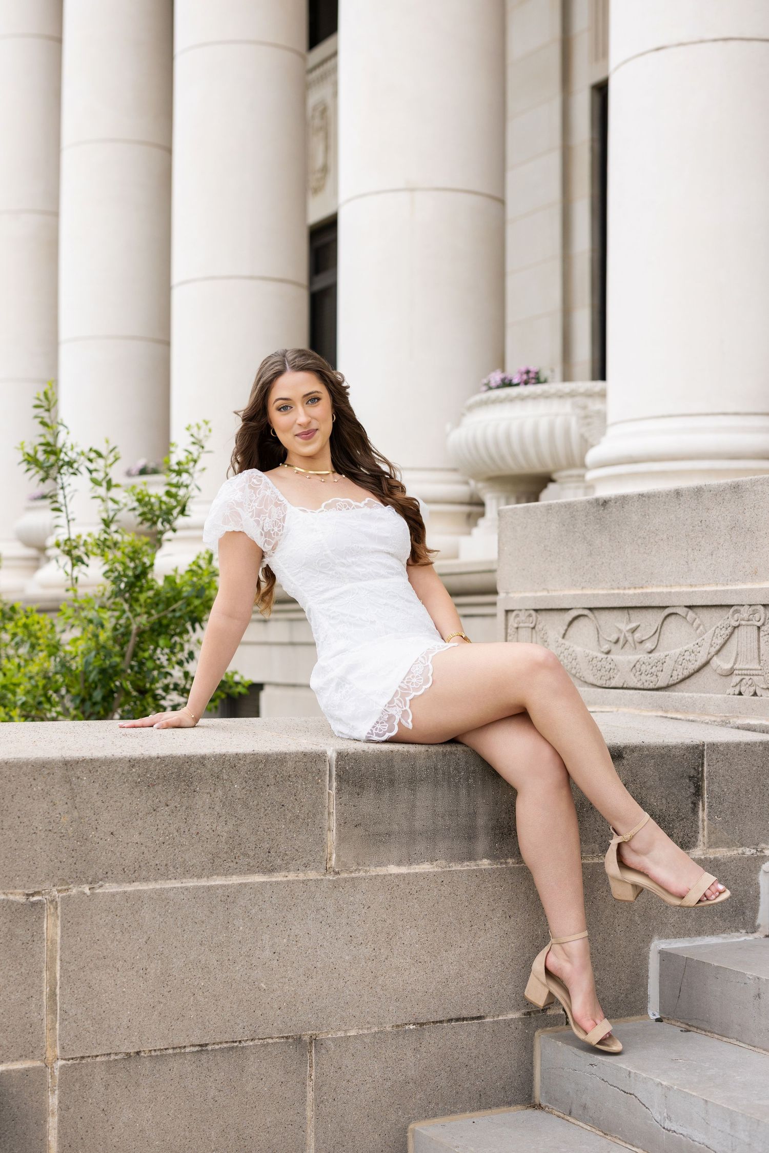 A white lace summer dress ensemble photographed on stone steps with decorative columns and urns in the background.
