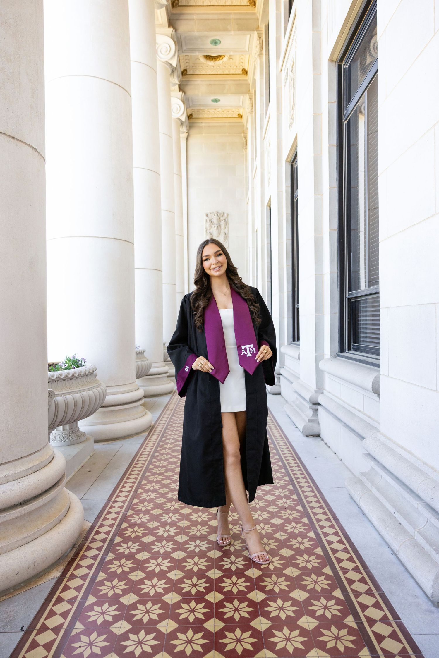 Elegant covered walkway with ornate tile flooring and classical white columns features a purple and black outfit on display.