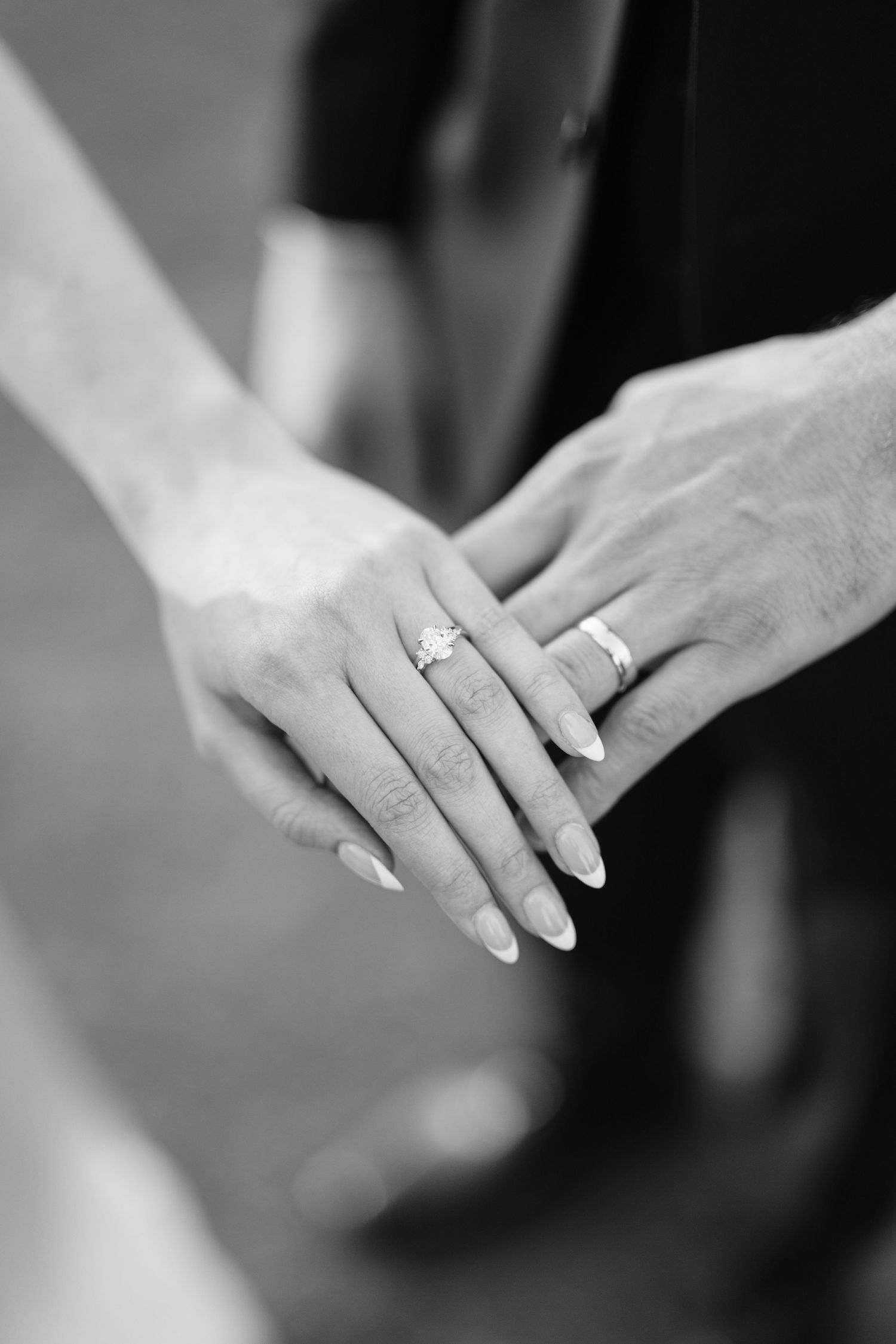 Black and white close-up of two hands with wedding rings touching gently, showing newly married couple's rings.