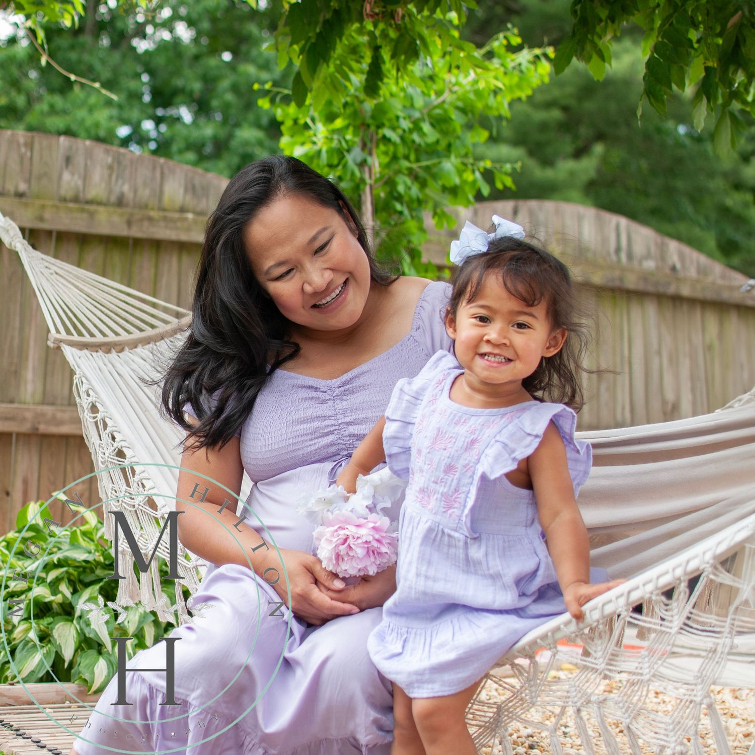 Photo of mom and daughter on a hammock in a backyard garden setting.