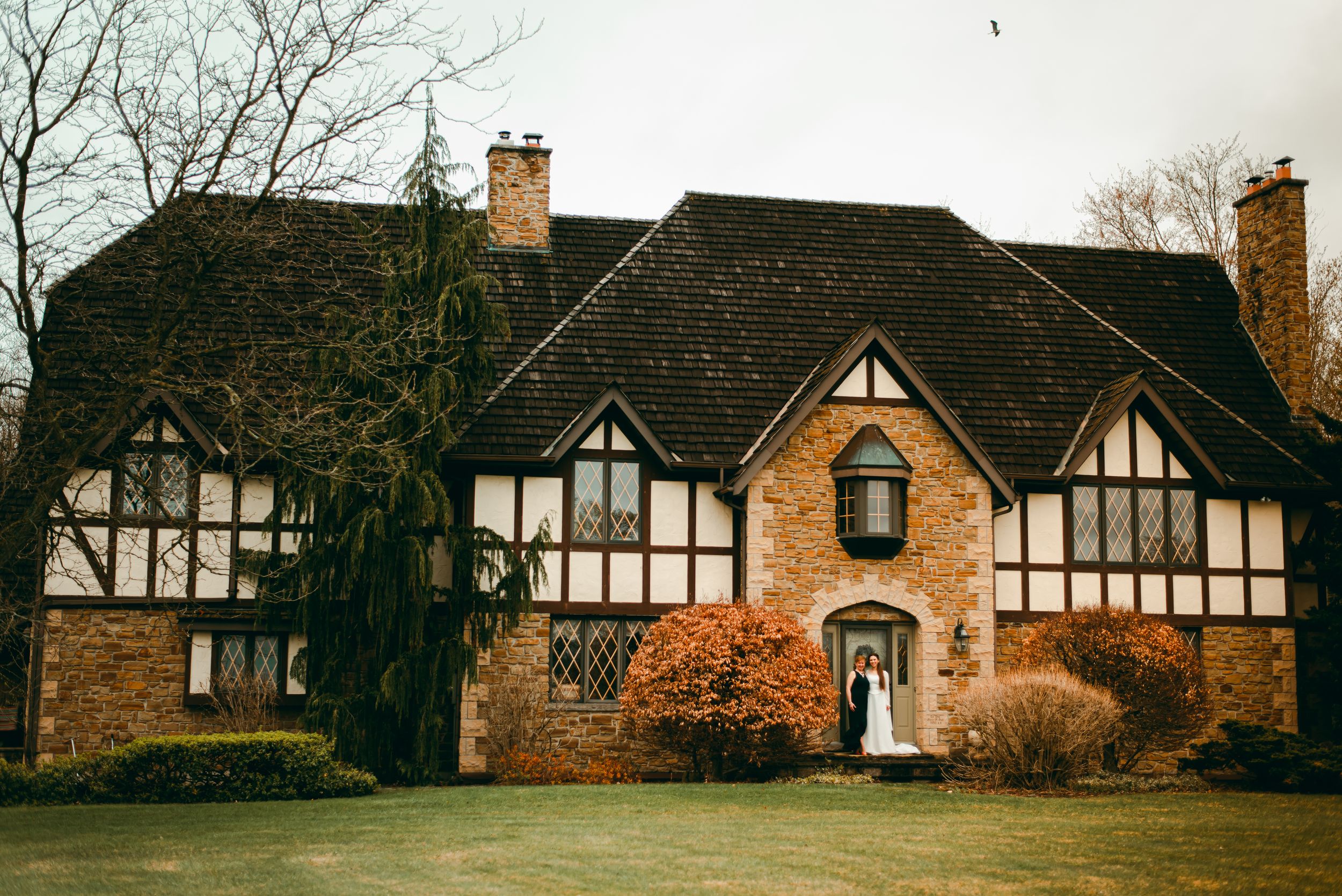 Bride and her mother standing in front of beautiful large cottage style house