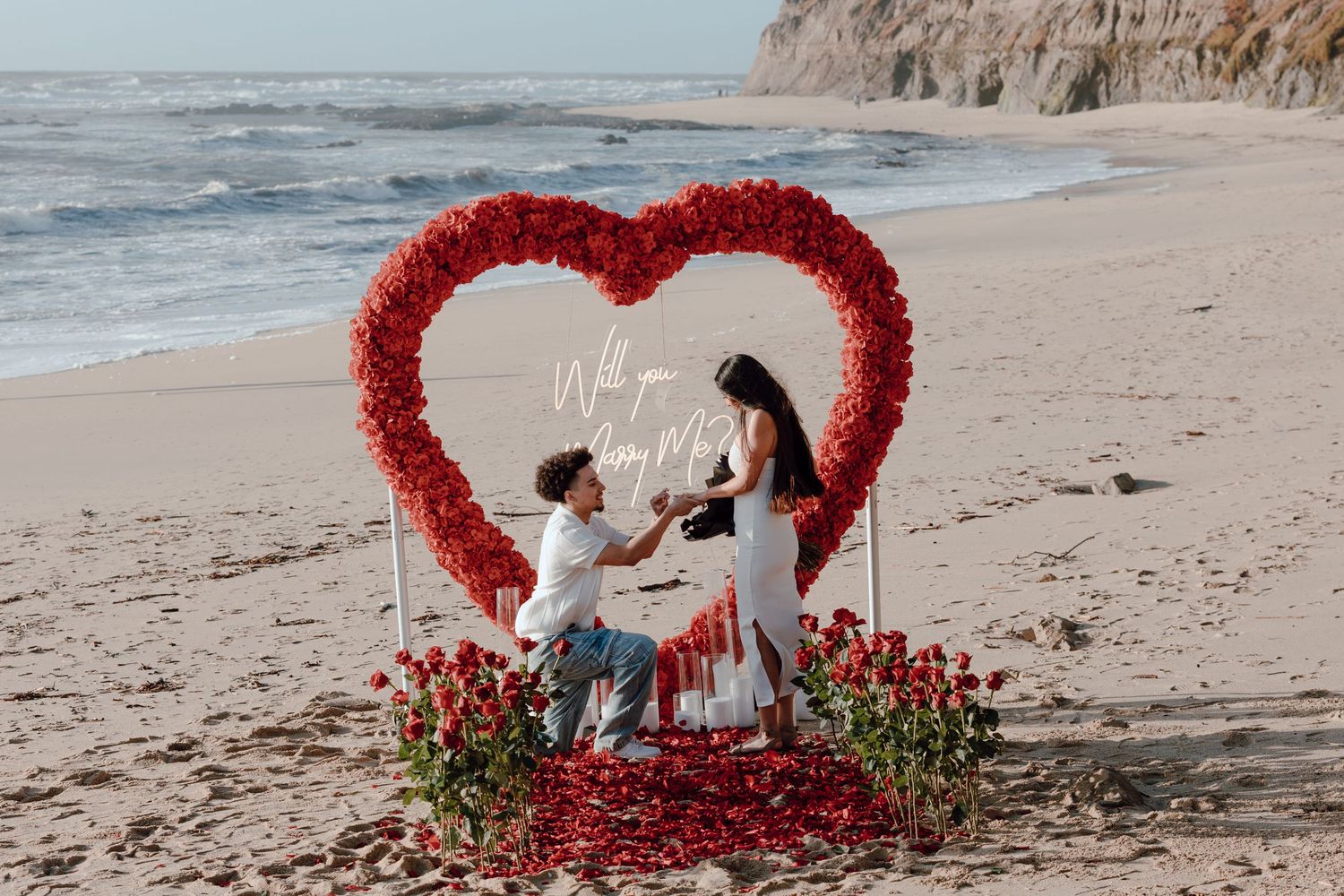 Scenic coastal proposal moment on rocky cliffs overlooking the Pacific Ocean with dramatic fog rolling in.