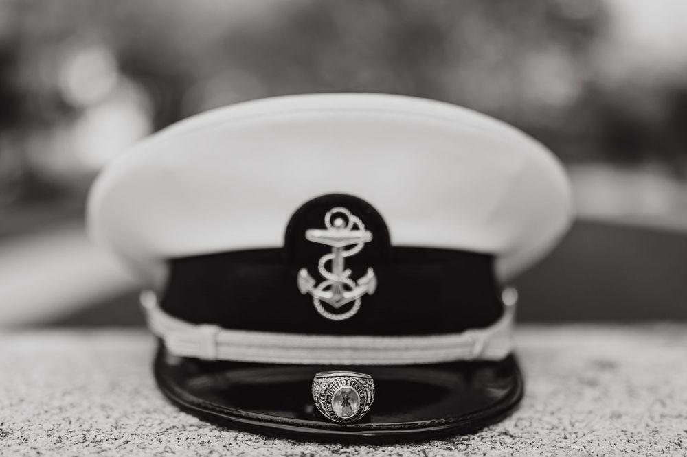 Navy officer's dress cap with anchor emblem shown in black and white photography.