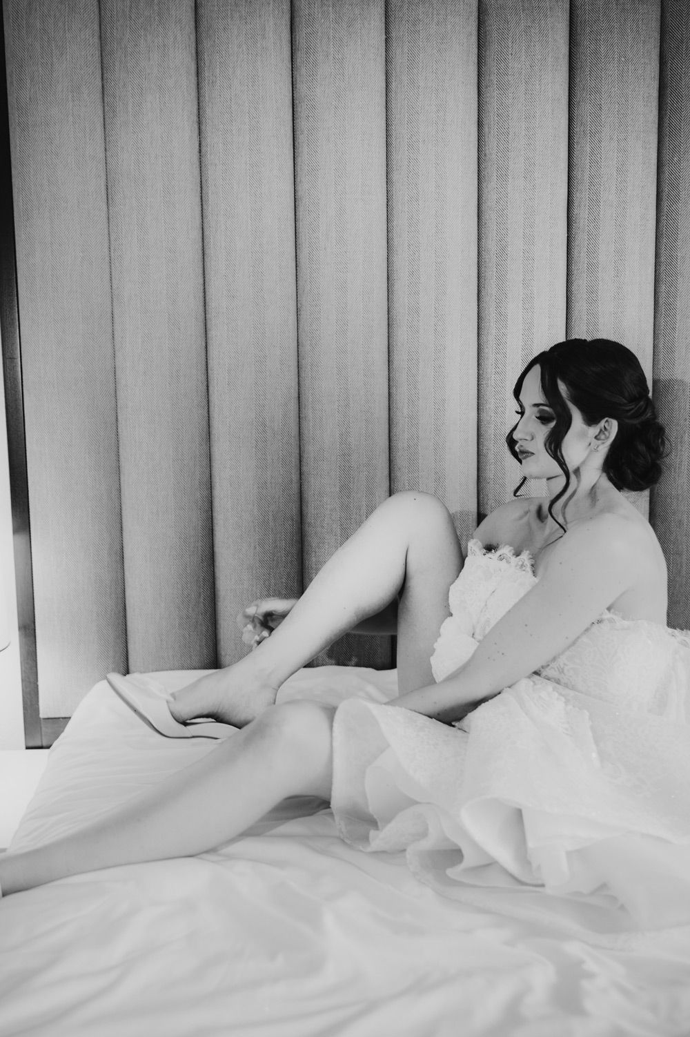 Intimna boudoir scena: mladenka leži na krevetu s nježnim osmijehom, okružena svilenim plahtama i svjetlom jutra.