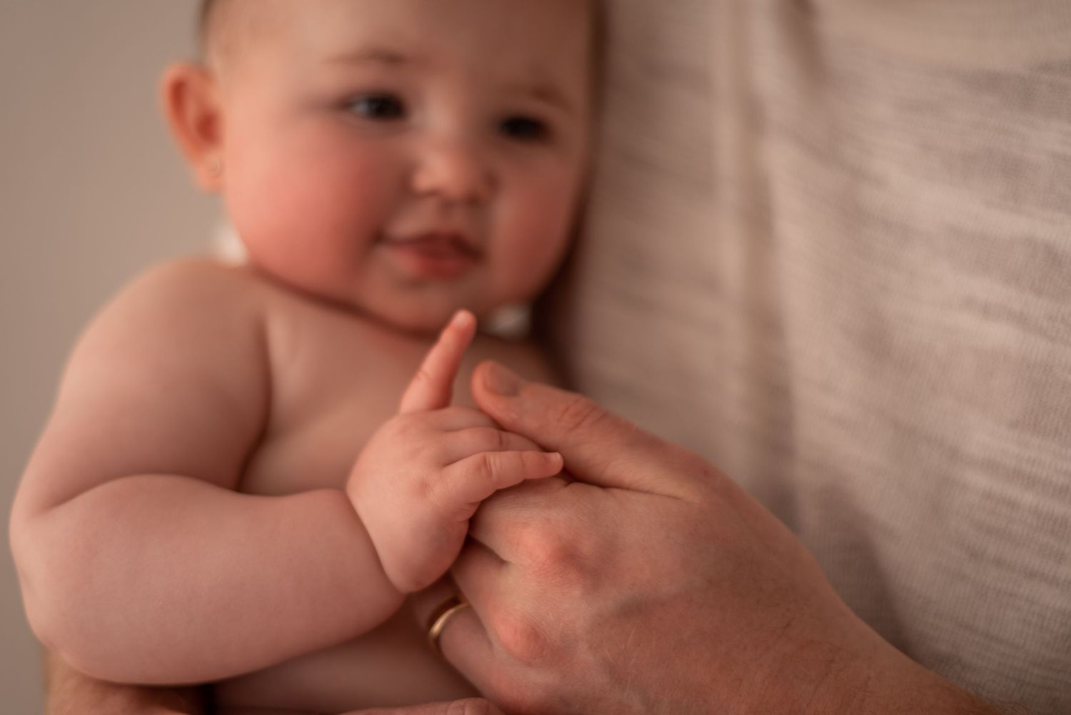 Close-up of tiny baby fingers reaching out in warm, soft lighting.