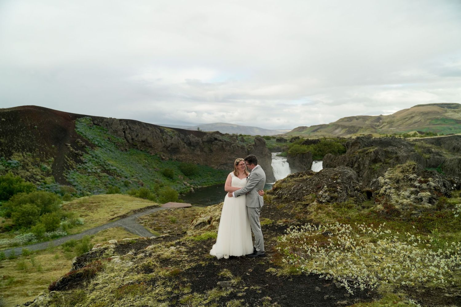 Couple eloping in front of Hjalparfoss waterfall in Iceland by Love and Lava Photo