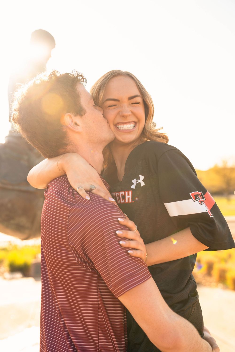 Joyful couple embracing and laughing together during golden hour sunset.