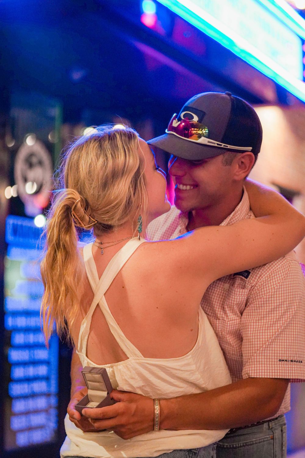 Intimate couple dancing together under blue neon lights at a nightclub.
