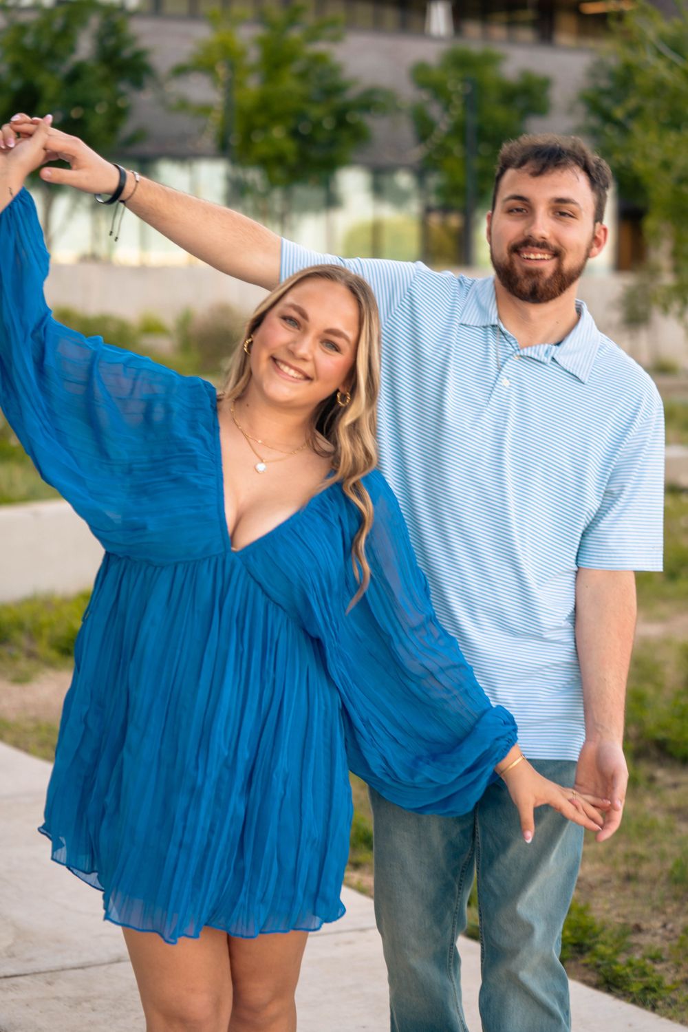 A couple shares a joyful moment outdoors, with the woman in a flowing blue dress.