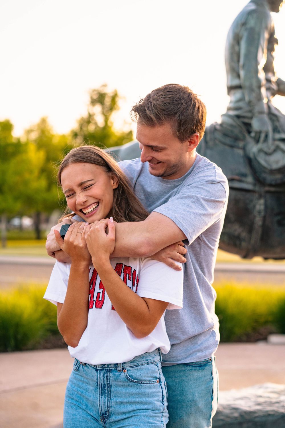 A candid moment of laughter and embracing by a campus statue.