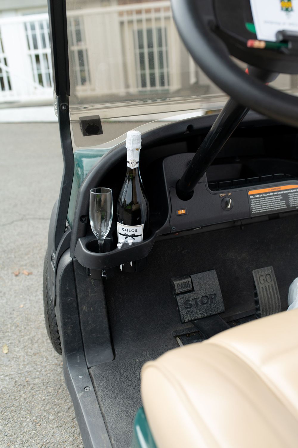Champagne bottle and glasses sit in a golf cart cup holder.
