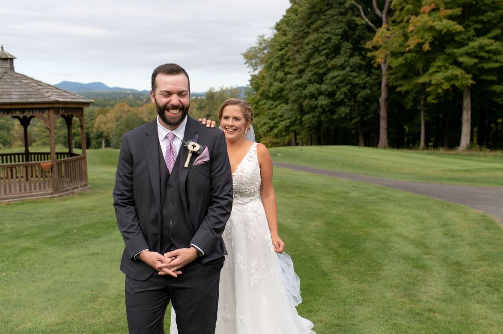 Couple poses in formal wedding attire on a lush golf course with mountains in background.