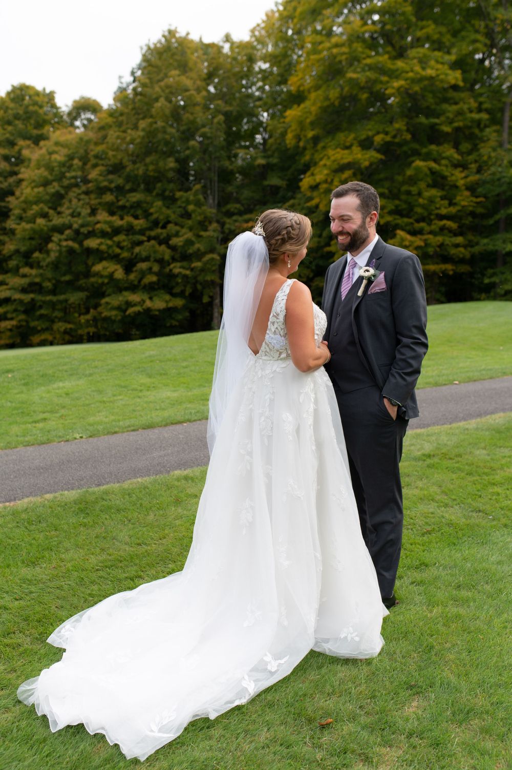 Wedding couple shares an intimate moment on a scenic path surrounded by autumn trees.