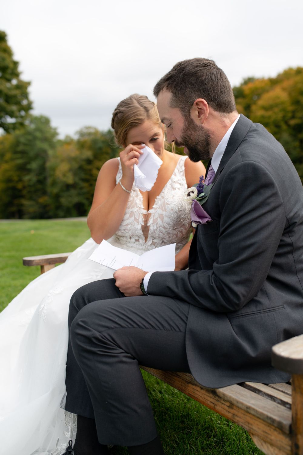Wedding couple shares an emotional intimate moment while sitting on a bench in an outdoor garden setting.