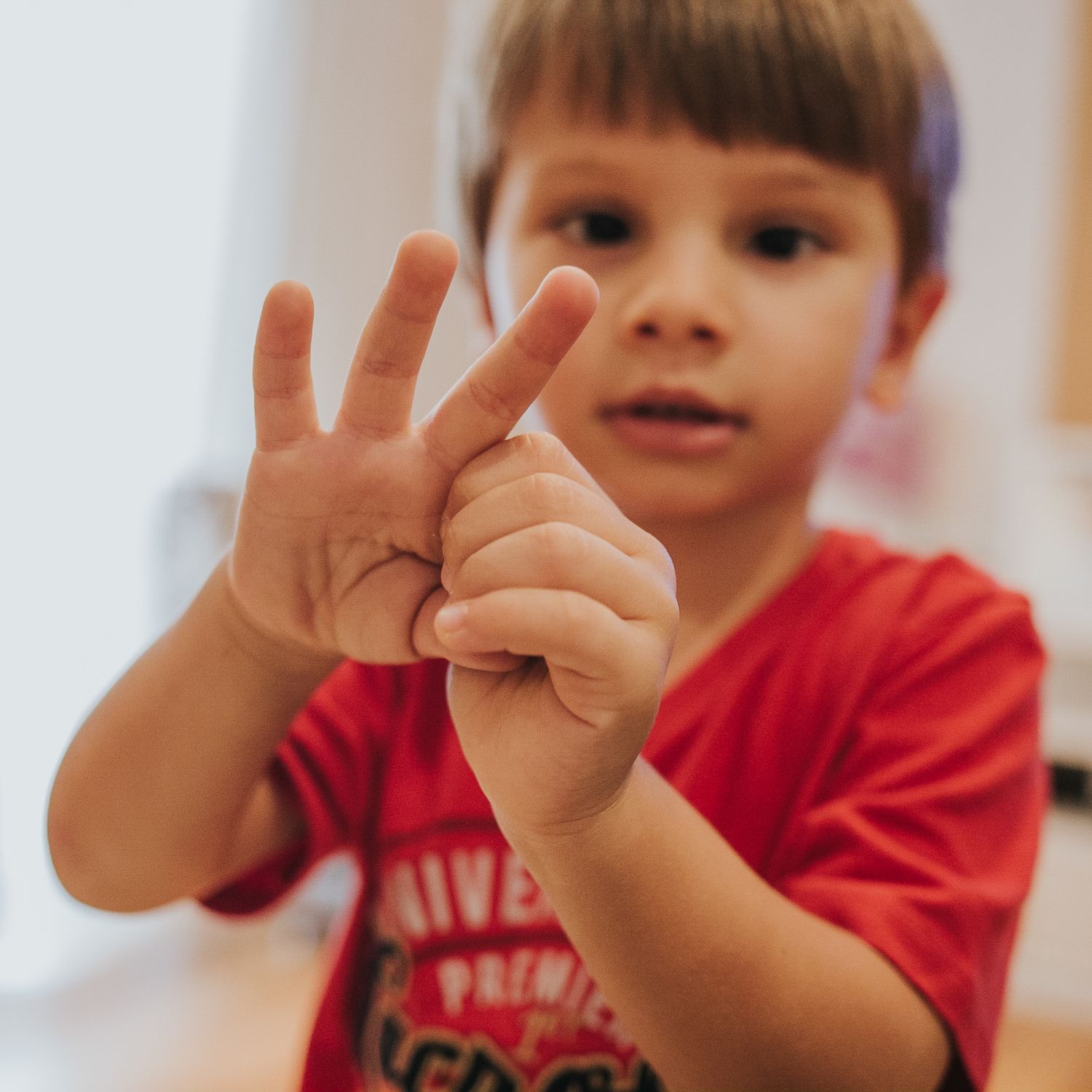 niño enseña que tiene 3 anos con los dedos. fotografía cotidiana infantil, cumpleaños y fiestas