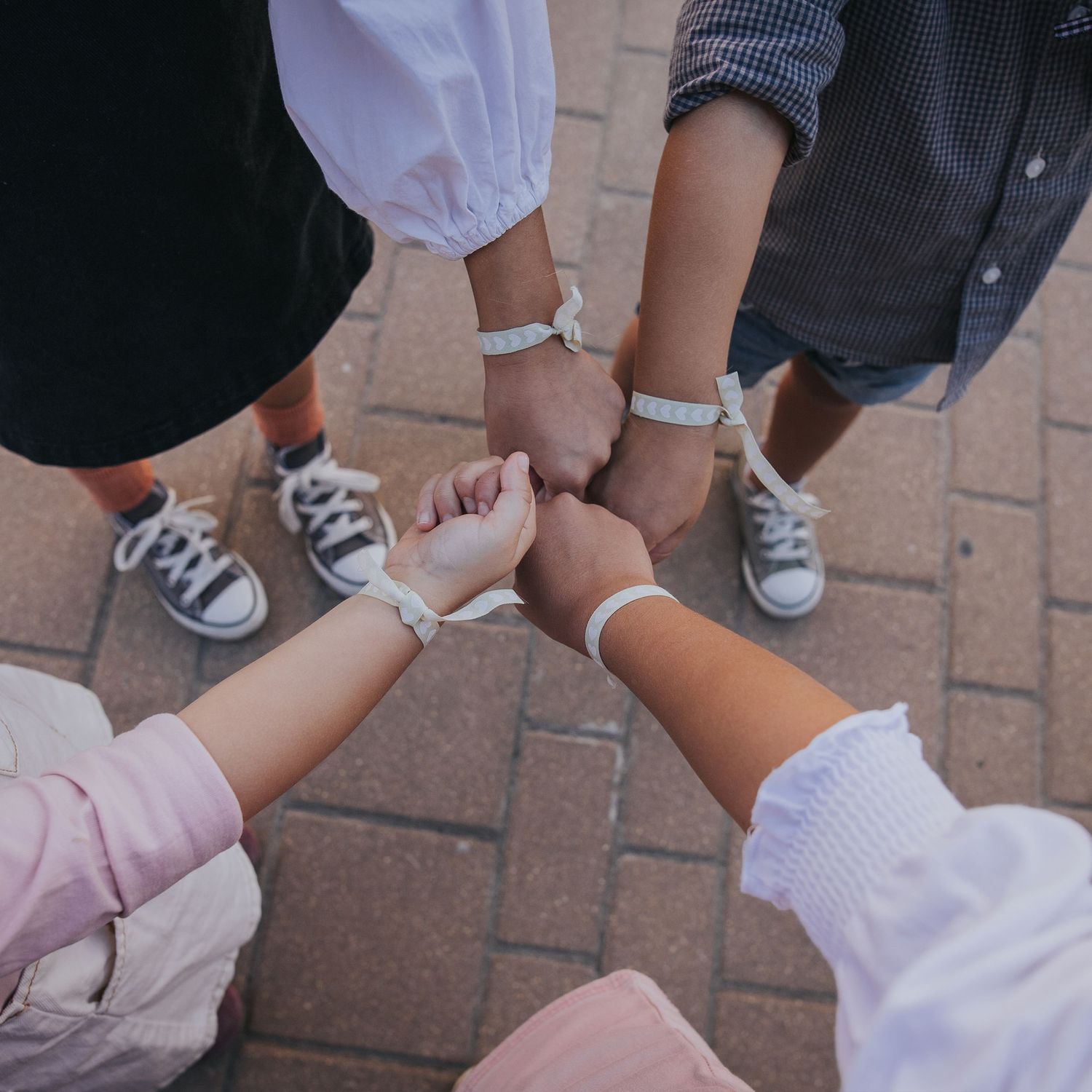 manitas de 4 niños amigos y sus pulseras iguales. amistad y infancia fin de vacaciones