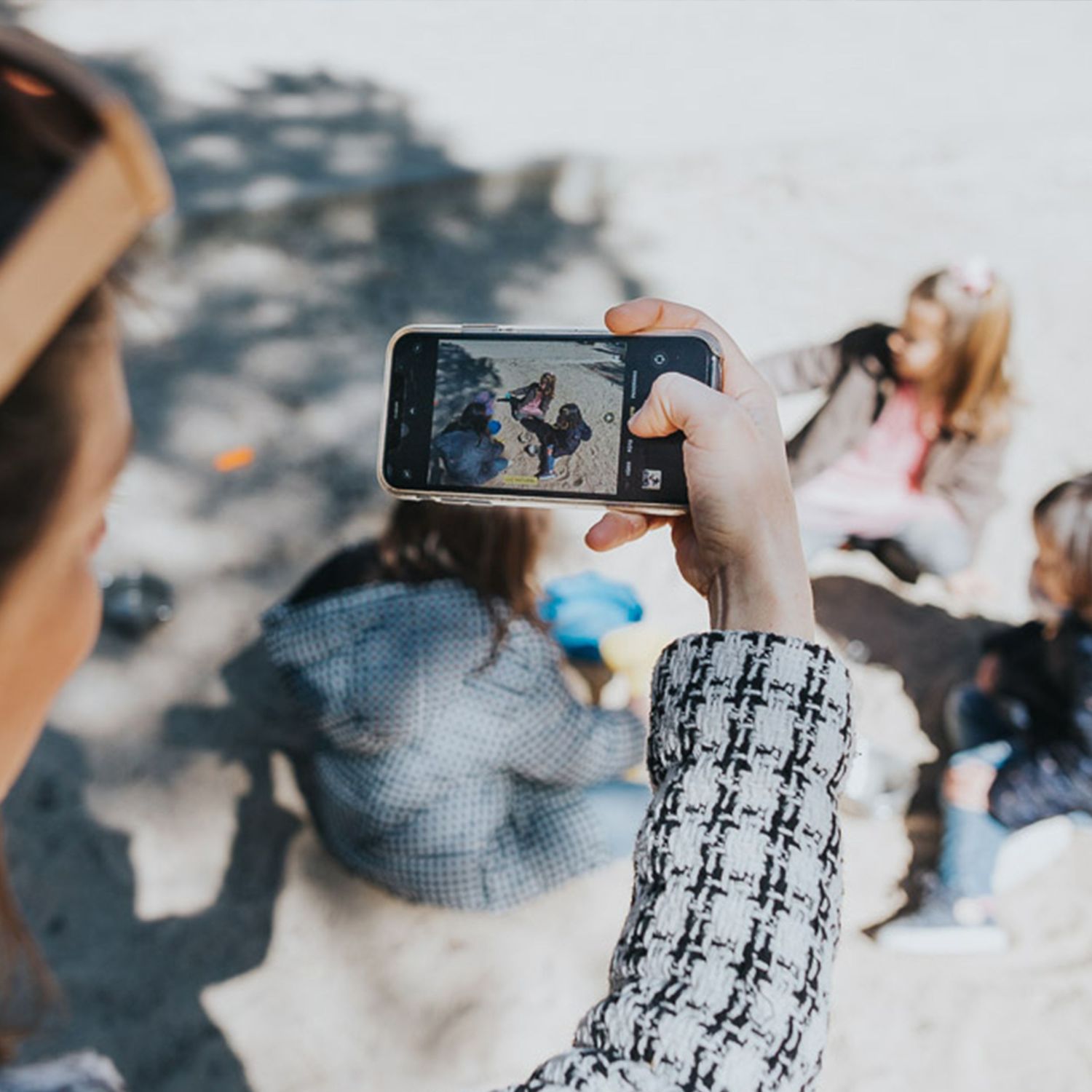 mama tomando foto de niñas jugando en arena del parque. vida real. foto natural sin posados.