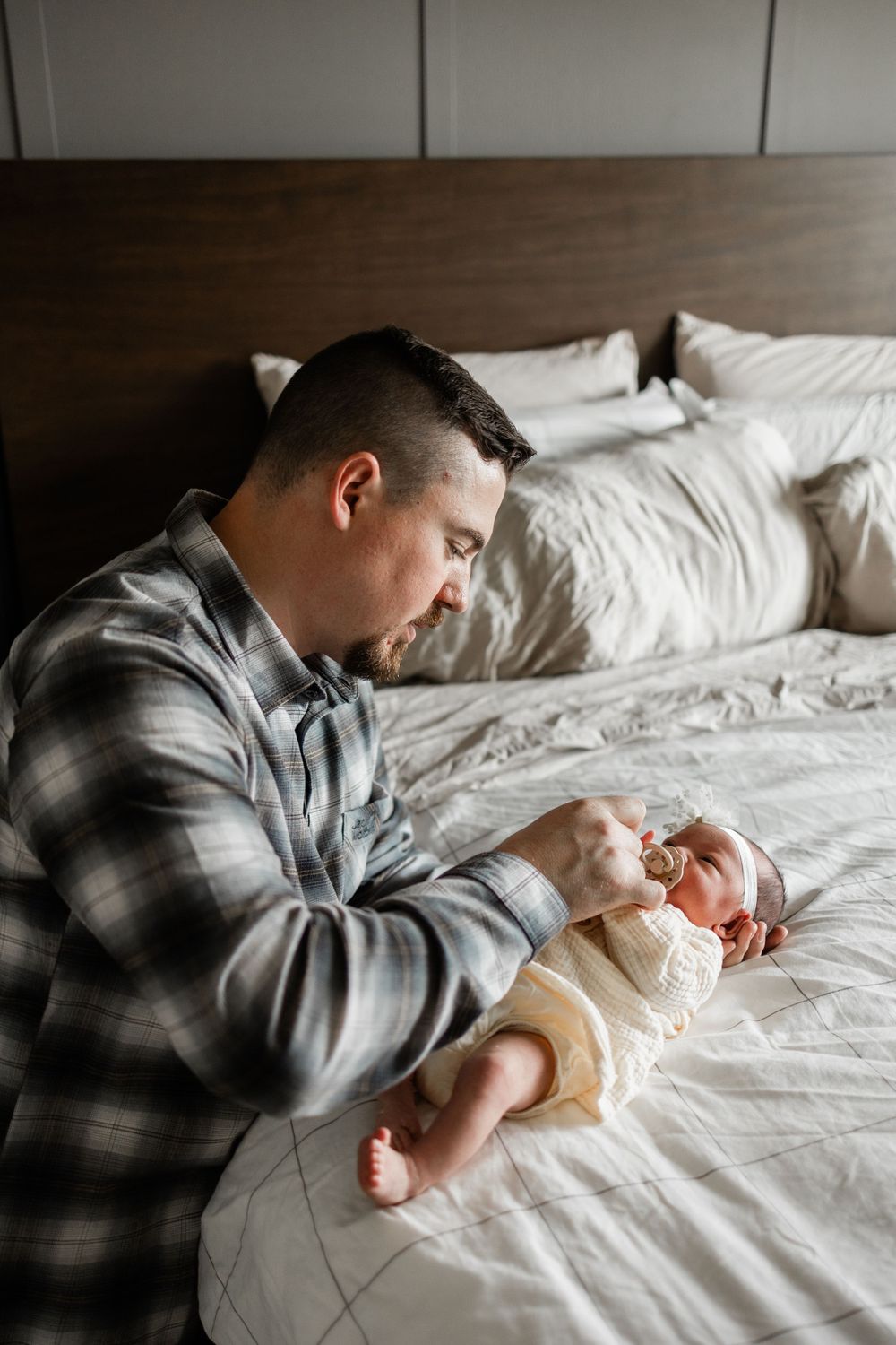 An intimate moment between parent and newborn on white bedding.