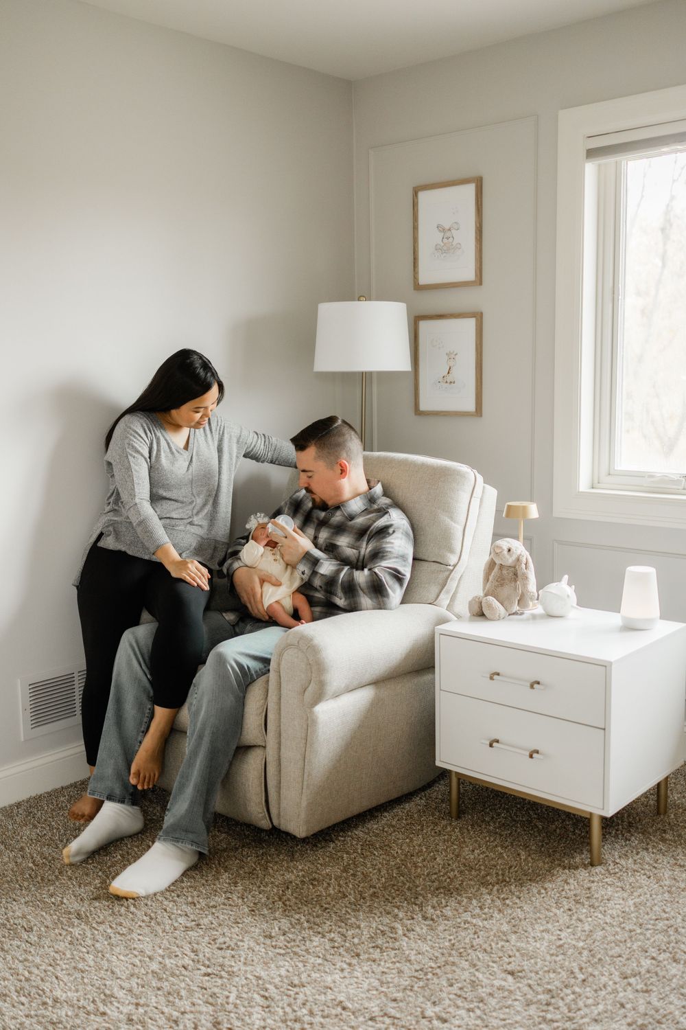 Intimate family moment in a serene nursery with neutral decor and natural lighting.