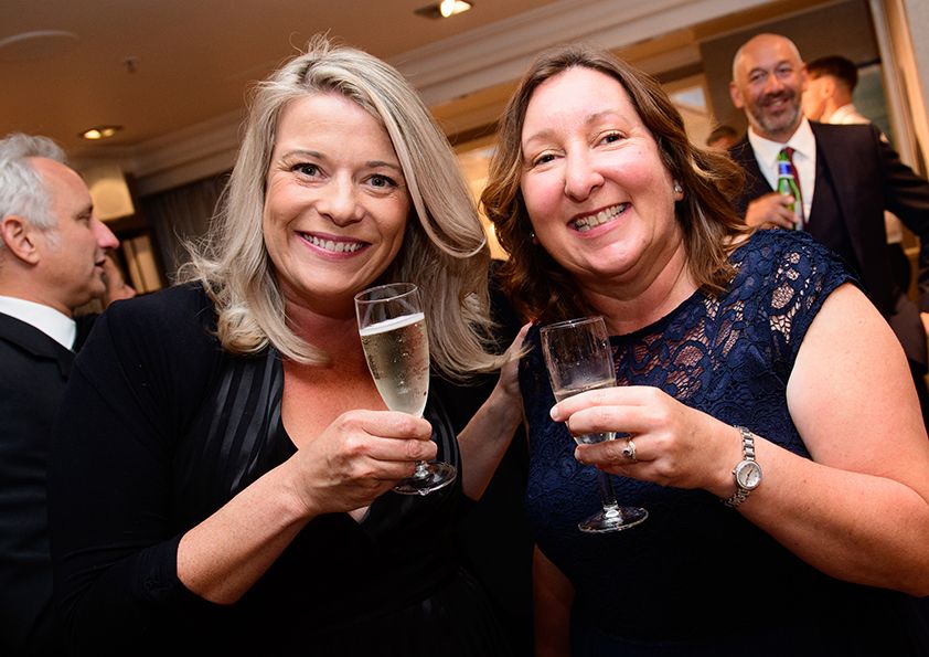 Two attendees enjoying drinks and conversation at an evening social gathering.