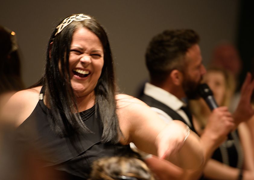 A guest laughing during a celebration event with festive lighting.