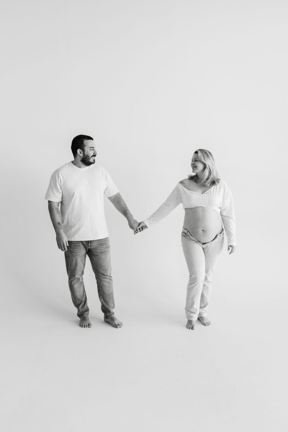 Couple holding hands for maternity photo session in black and white at toronto icon studio space