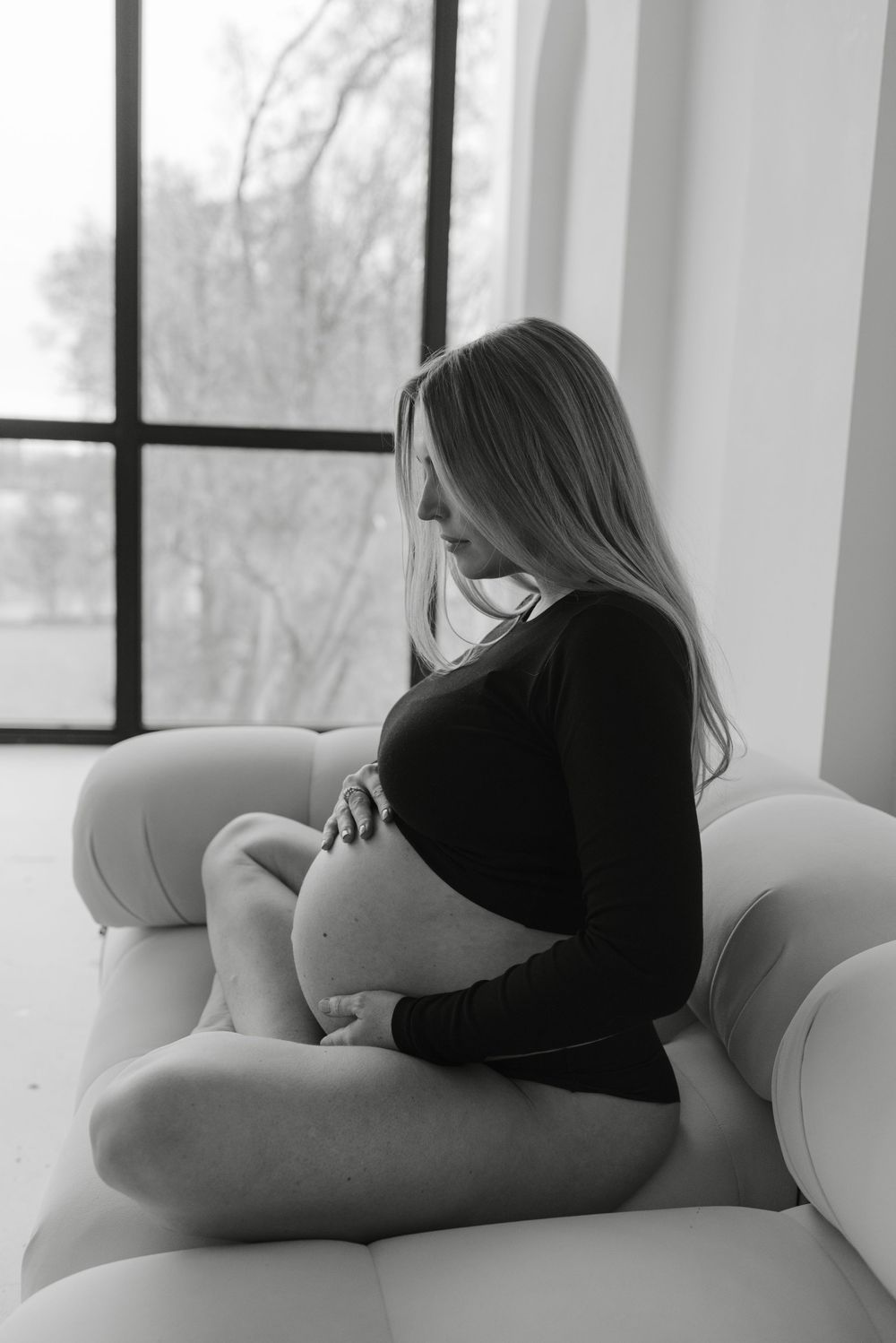 Pregnant woman sitting in profile on a couch during a maternity photoshoot at Icon Studio in Toronto, captured by Maternity Photographer