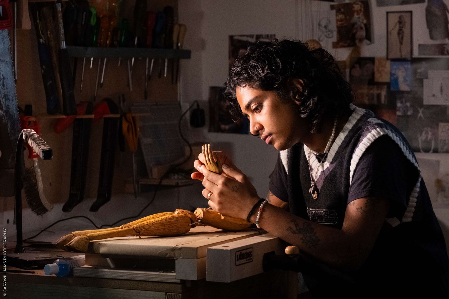 Craftsperson working intently on detailed project in dimly lit workshop.