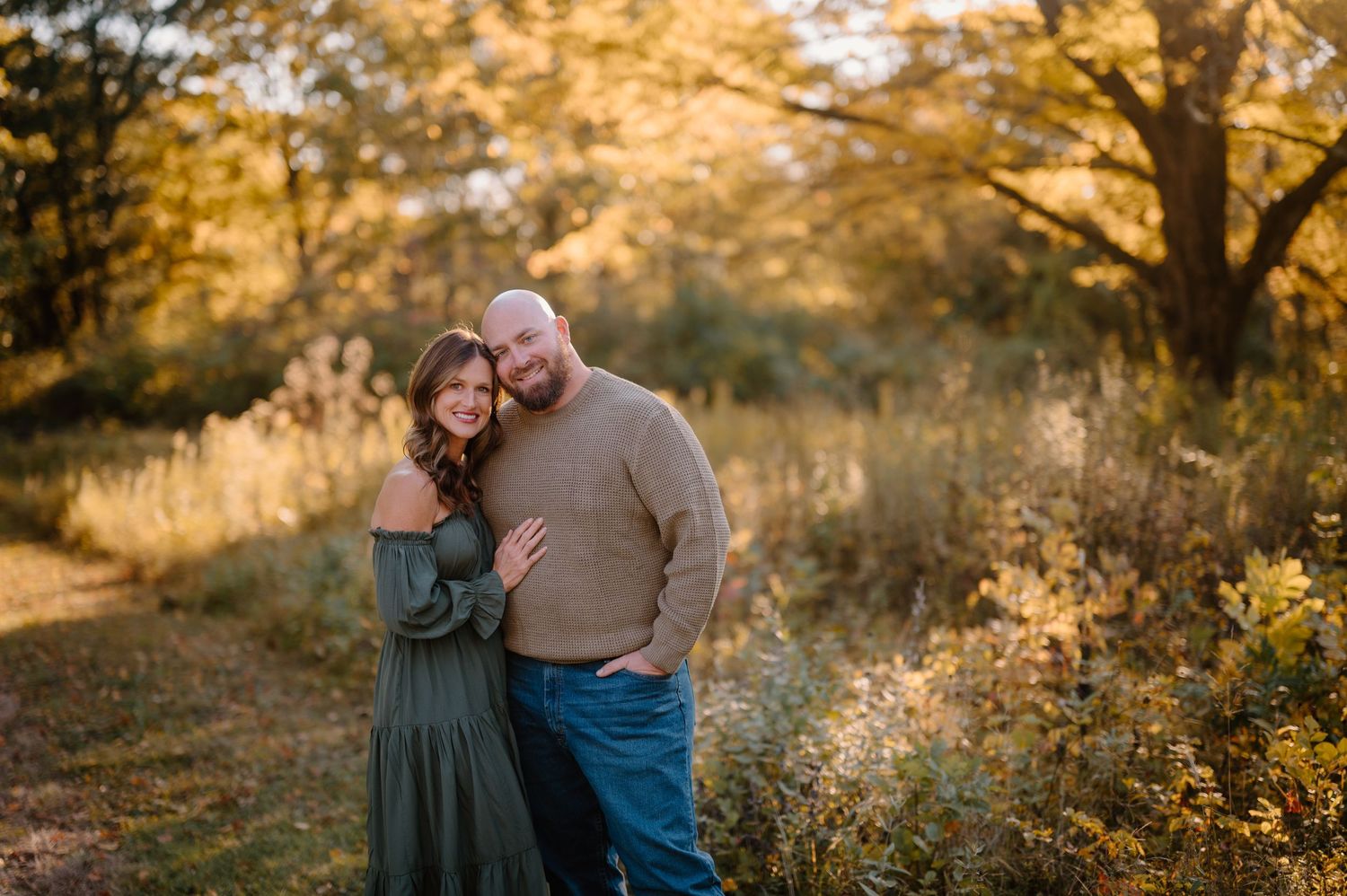 A couple embraces tenderly in a park surrounded by beautiful orange autumn foliage during a romantic photoshoot.