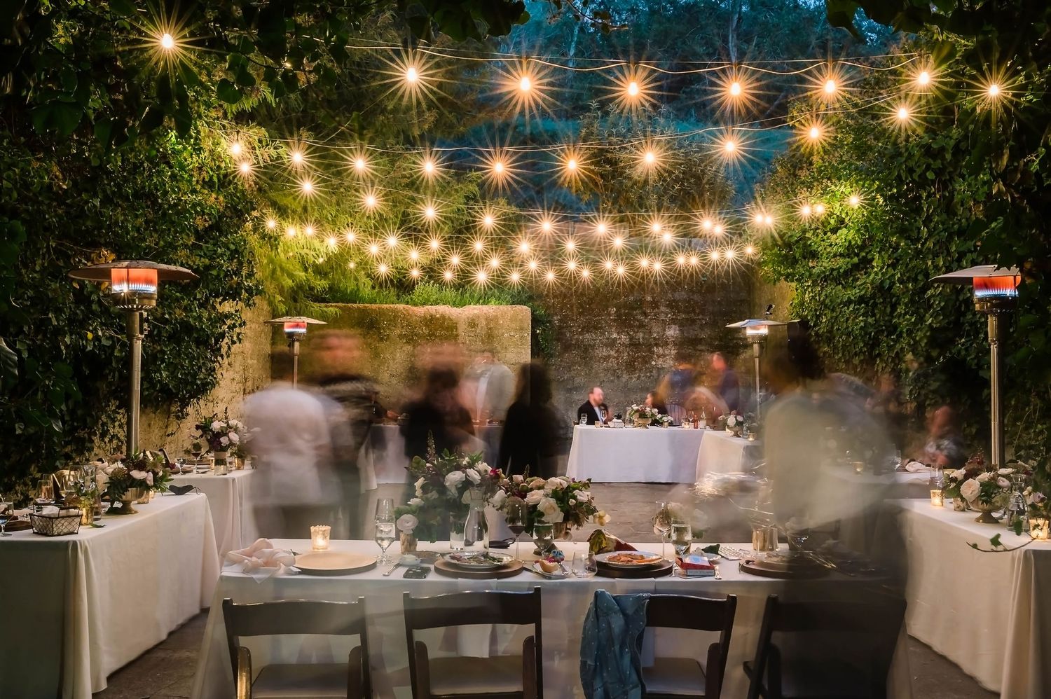 Wedding reception table decorated with string lights and lush greenery creating an intimate garden atmosphere.
