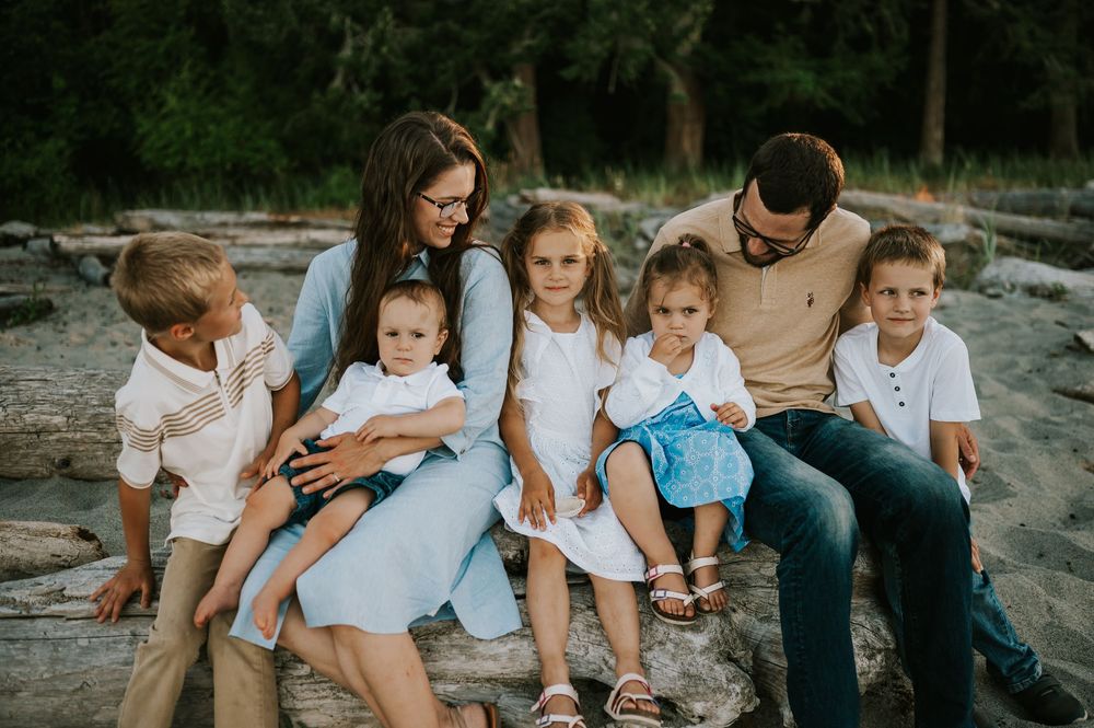 Comox Valley family photoshoot of mom and dad with five kids on driftwood Kye Bay Beach Portraits taken by photographer Soulfull Photographs