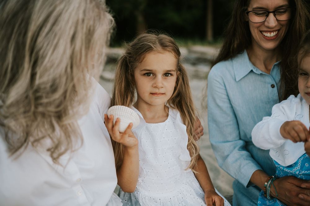 Comox Valley family photoshoot of girls snuggled up on log holding shell Kye Bay Beach Portraits taken by photographer Soulfull Photographs
