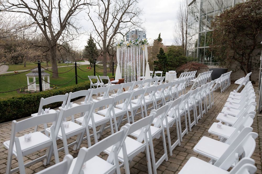 White folding chairs set up in rows outdoors for an elegant wedding ceremony.