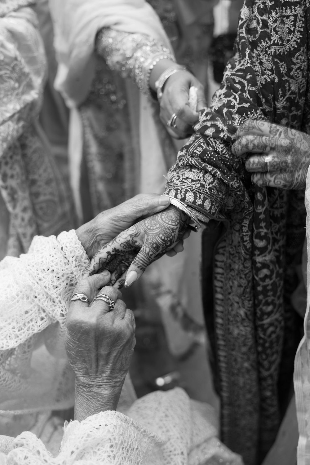 Close-up shot of hands showing intricate henna designs and bridal jewelry during a traditional South Asian wedding ceremony.