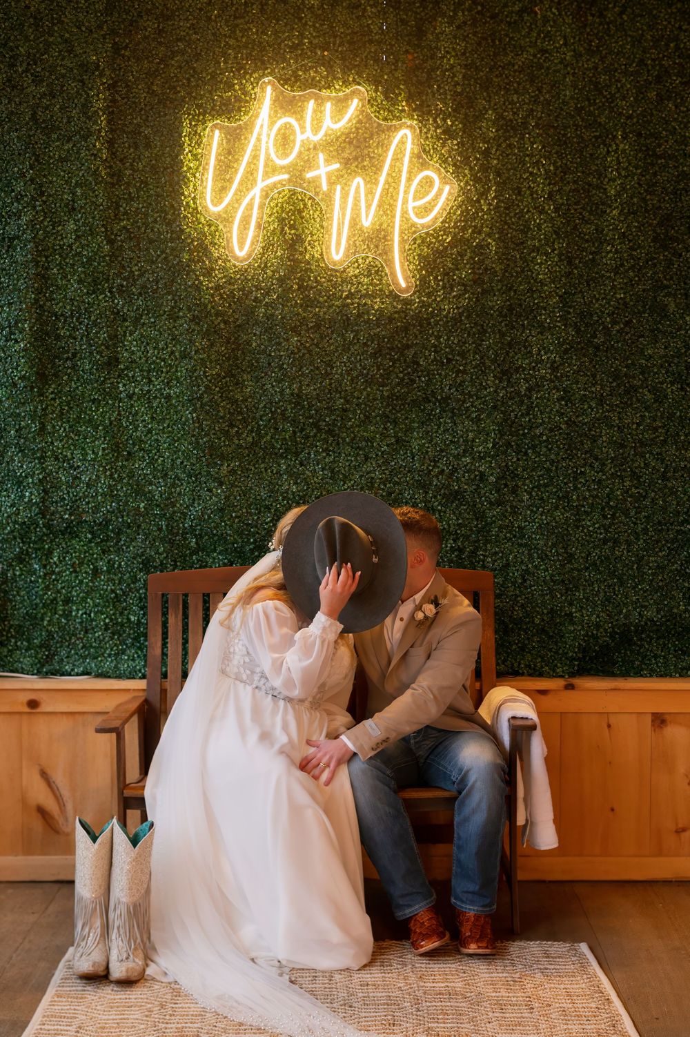 Wedding photos against a greenery wall with glowing neon sign decorations.