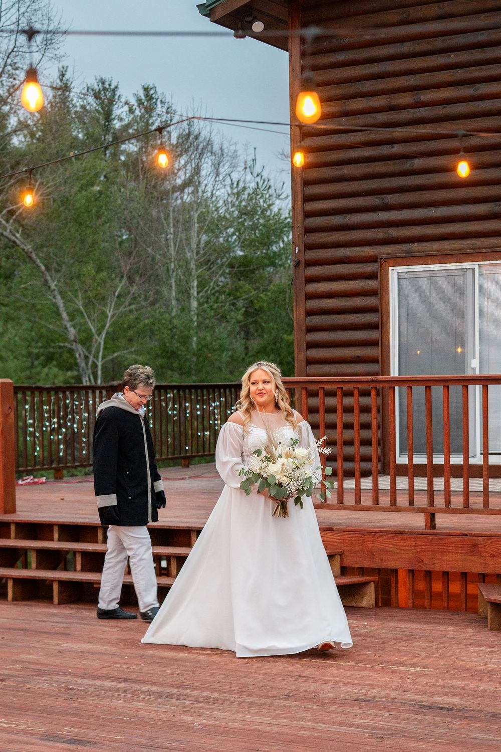 Wedding ceremony on a rustic cabin deck with mountain views and string lights.