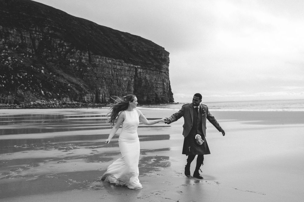 A romantic beach walk at the base of dramatic coastal cliffs in black and white photography.