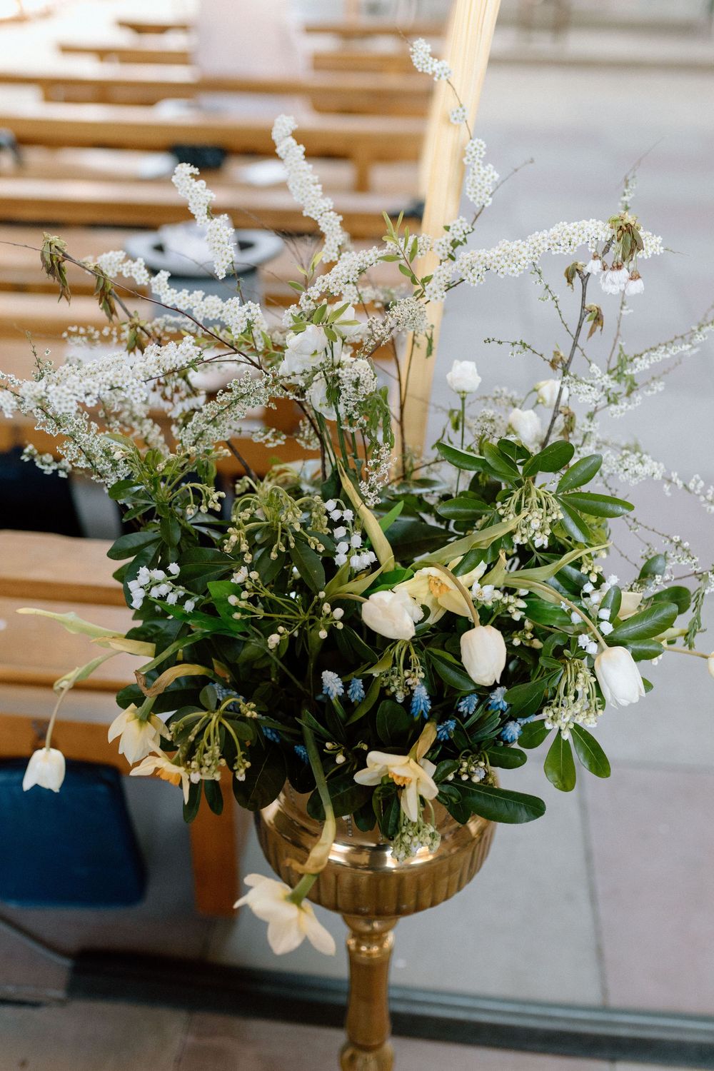 Elegant white and green floral arrangement in a gold chalice with delicate wildflowers and foliage for church decoration.