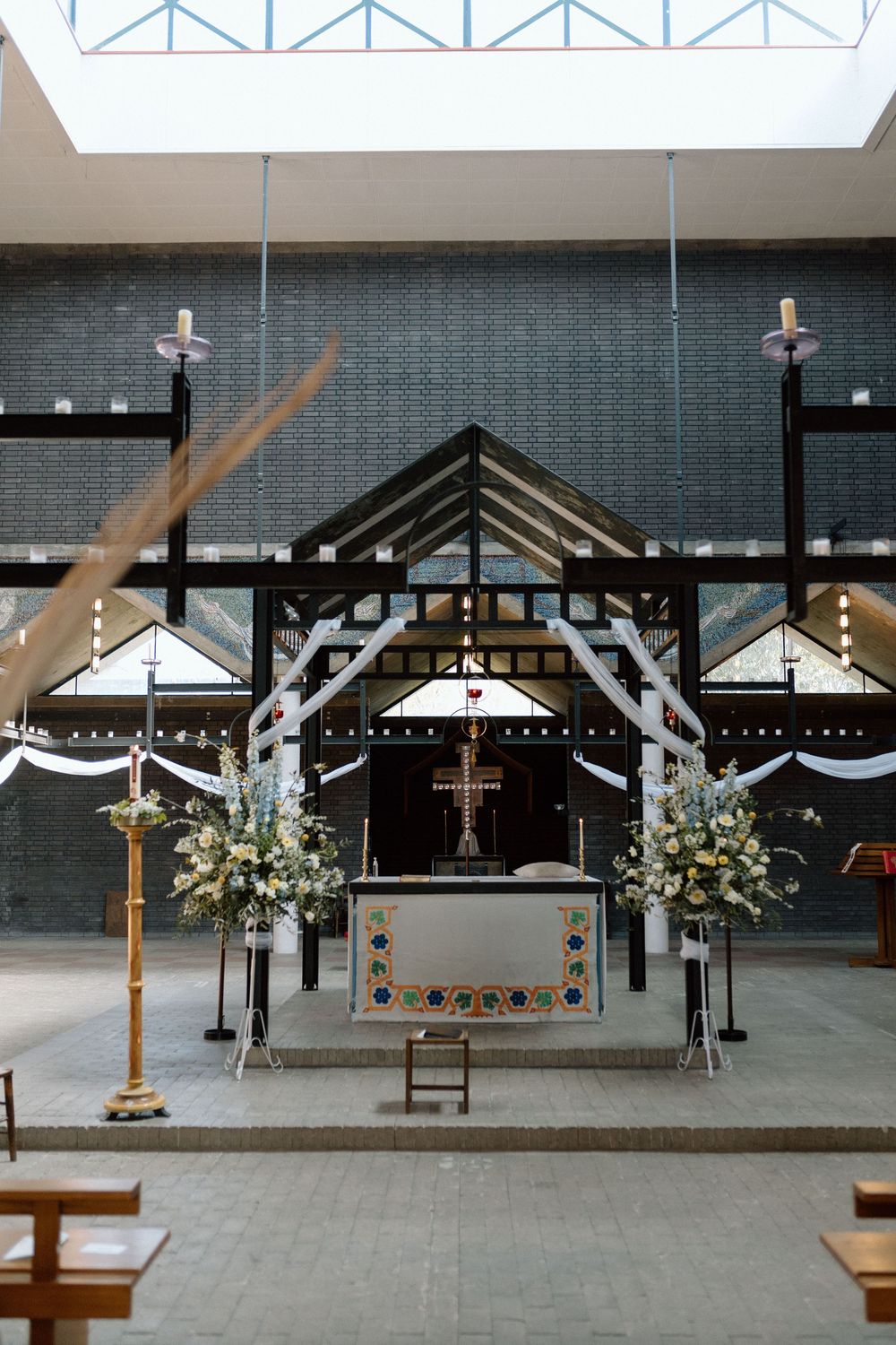 St Paul's Bow Common altar decorated with white fabric draping, floral arrangements and a wooden cross in minimalist interior space.