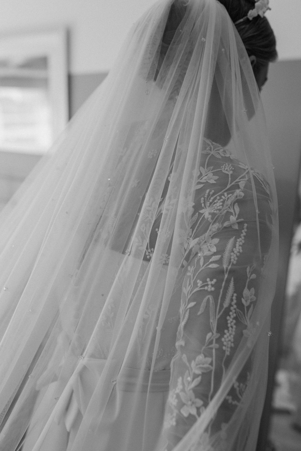 Close-up view of an elegant bridal veil with delicate floral lace embroidery in black and white.