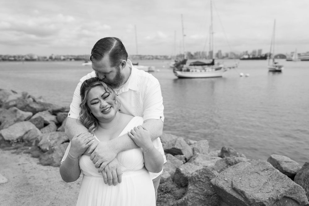 An engagement photoshoot at the harbor shows intimate moments of a couple posing along the waterfront.