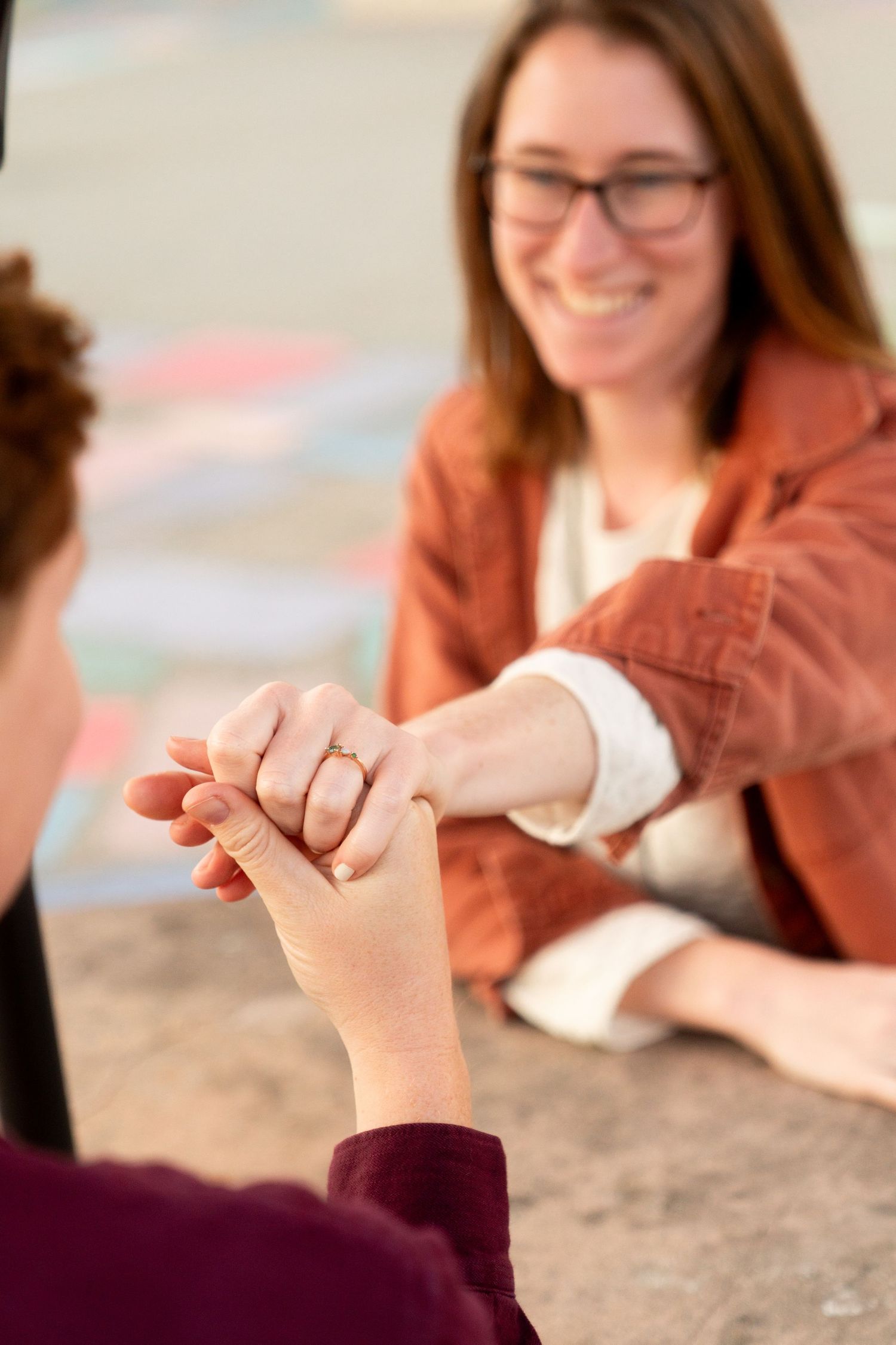 Two people hold hands across a counter while having an uplifting conversation in a casual setting.