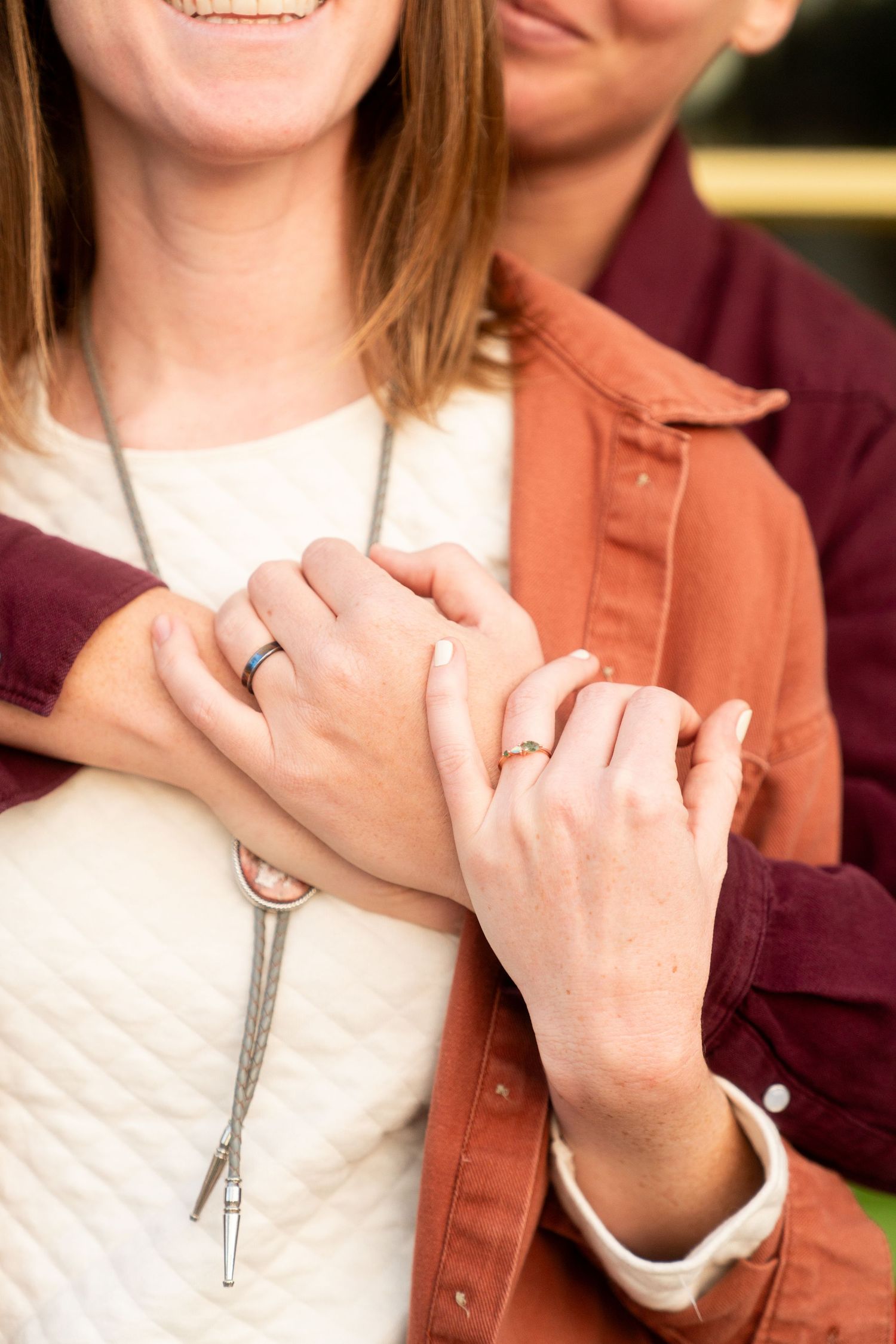 Close-up of engaged couple's hands with wedding rings clasped together showing affection.