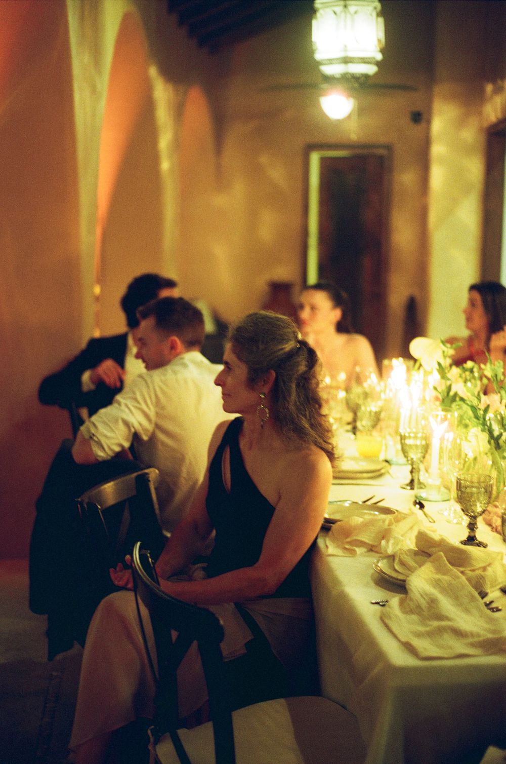 Candlelit dinner table at an elegant evening event with guests seated in formal attire.